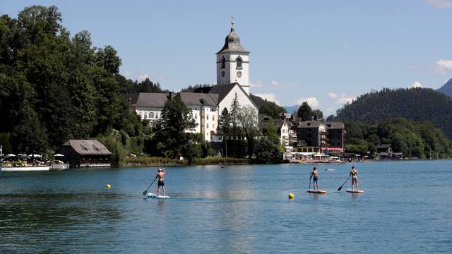 Stand-up paddlers are seen on Lake Wolfgangsee in front of St. Wolfgang