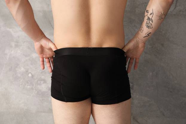 Young man in stylish black underwear near grey wall indoors, clo