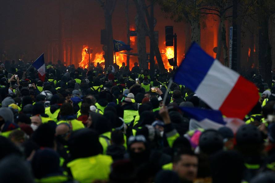 A French flag is held by protesters wearing yellow vests, a symbol of a drivers' protest against higher diesel taxes, who demonstrate near the Place de l'Etoile in Paris