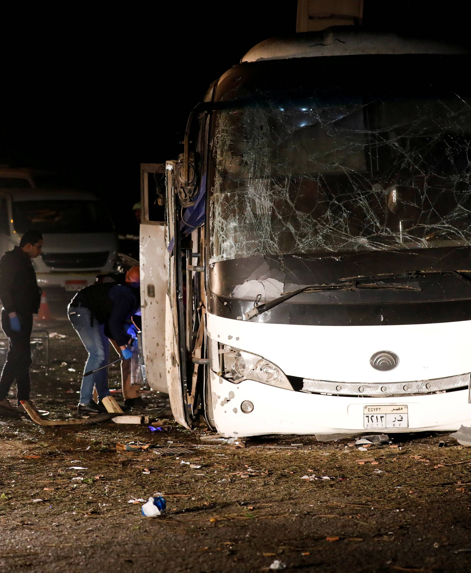 Police officers inspect a scene of a bus blast in Giza