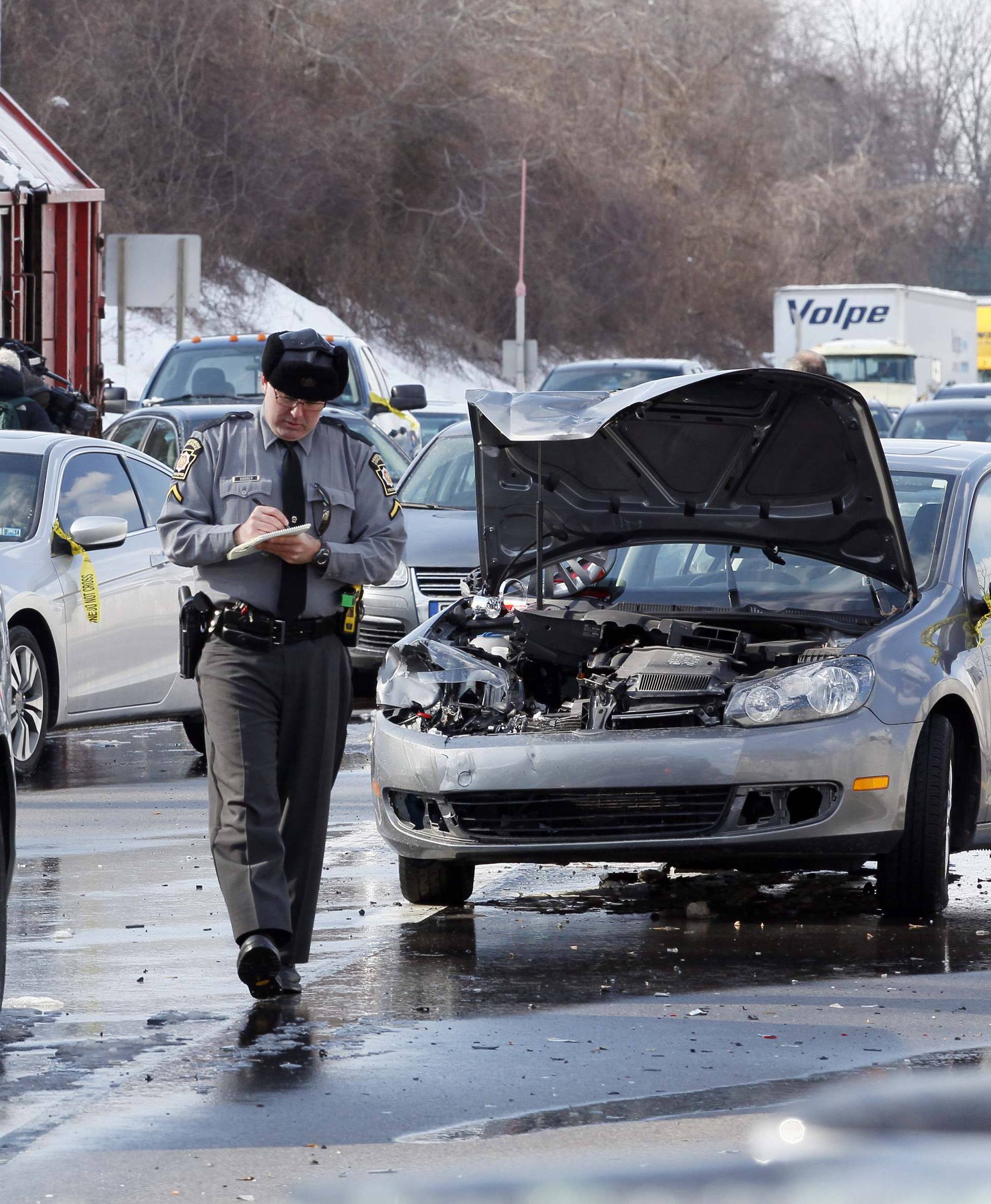 A Pennsylvania State Police Trooper is at the scene of an earlier multi-car and truck pile up during the morning commute on the Pennsylvania Turnpike near the Bensalem interchange