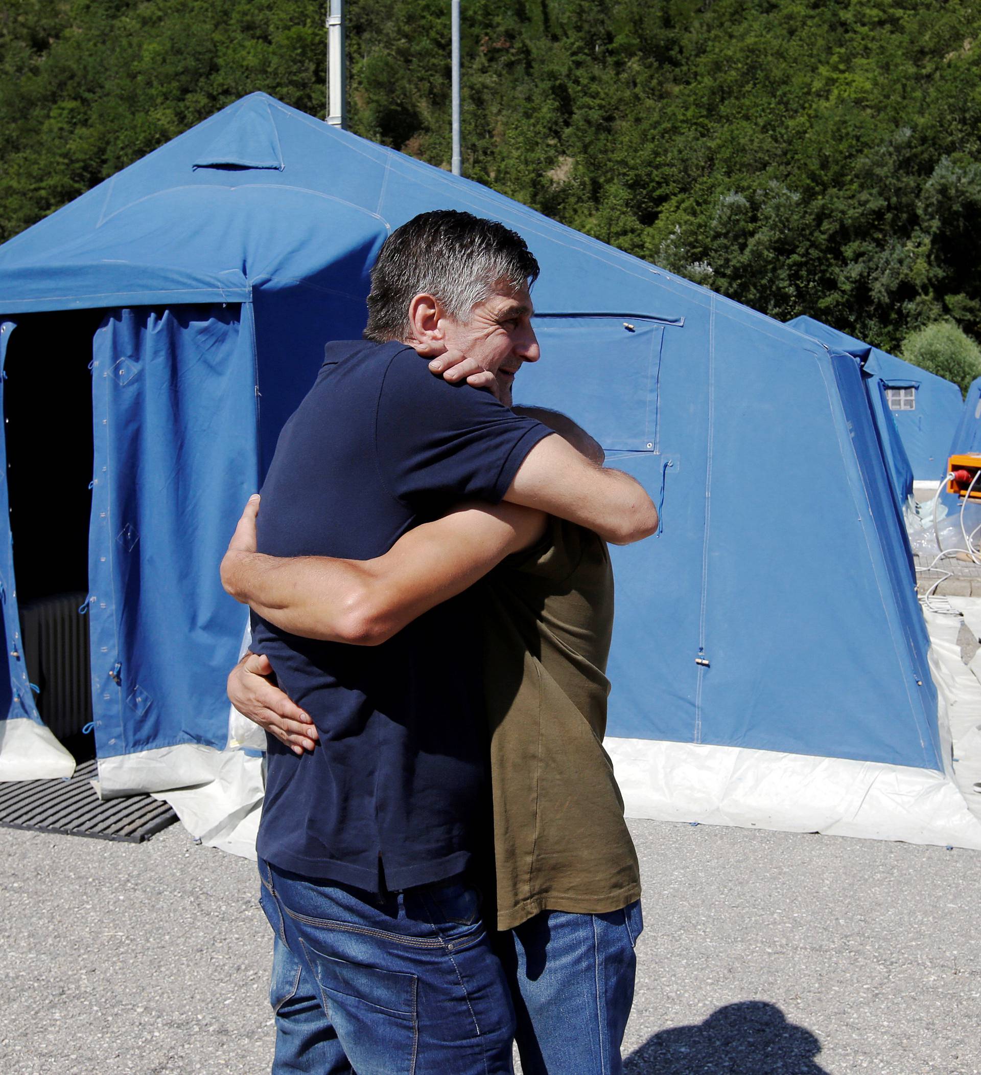 Two survivors hug at a tent camp set up as temporary shelter following an earthquake in Pescara del Tronto