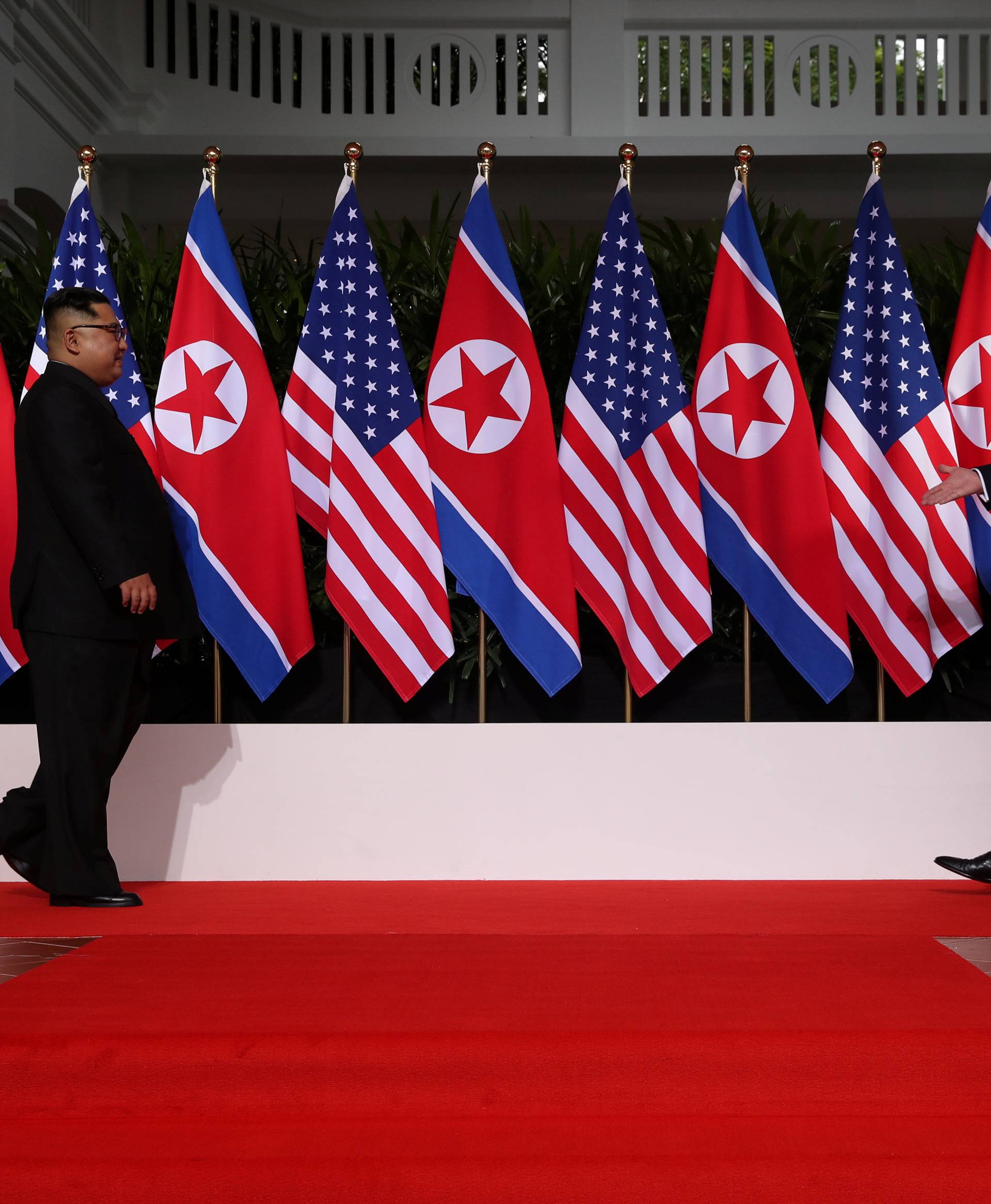 U.S. President Donald Trump and North Korean leader Kim Jong Un walk to shake hands at the Capella Hotel on Sentosa island in Singapore