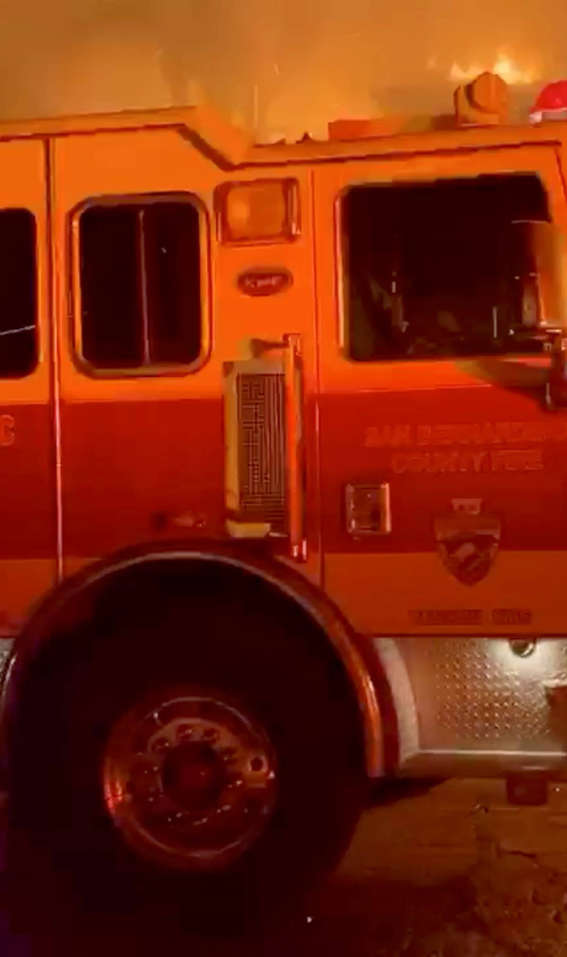 A fire engine is seen in front of a burning house during wildfires in San Bernardino, California