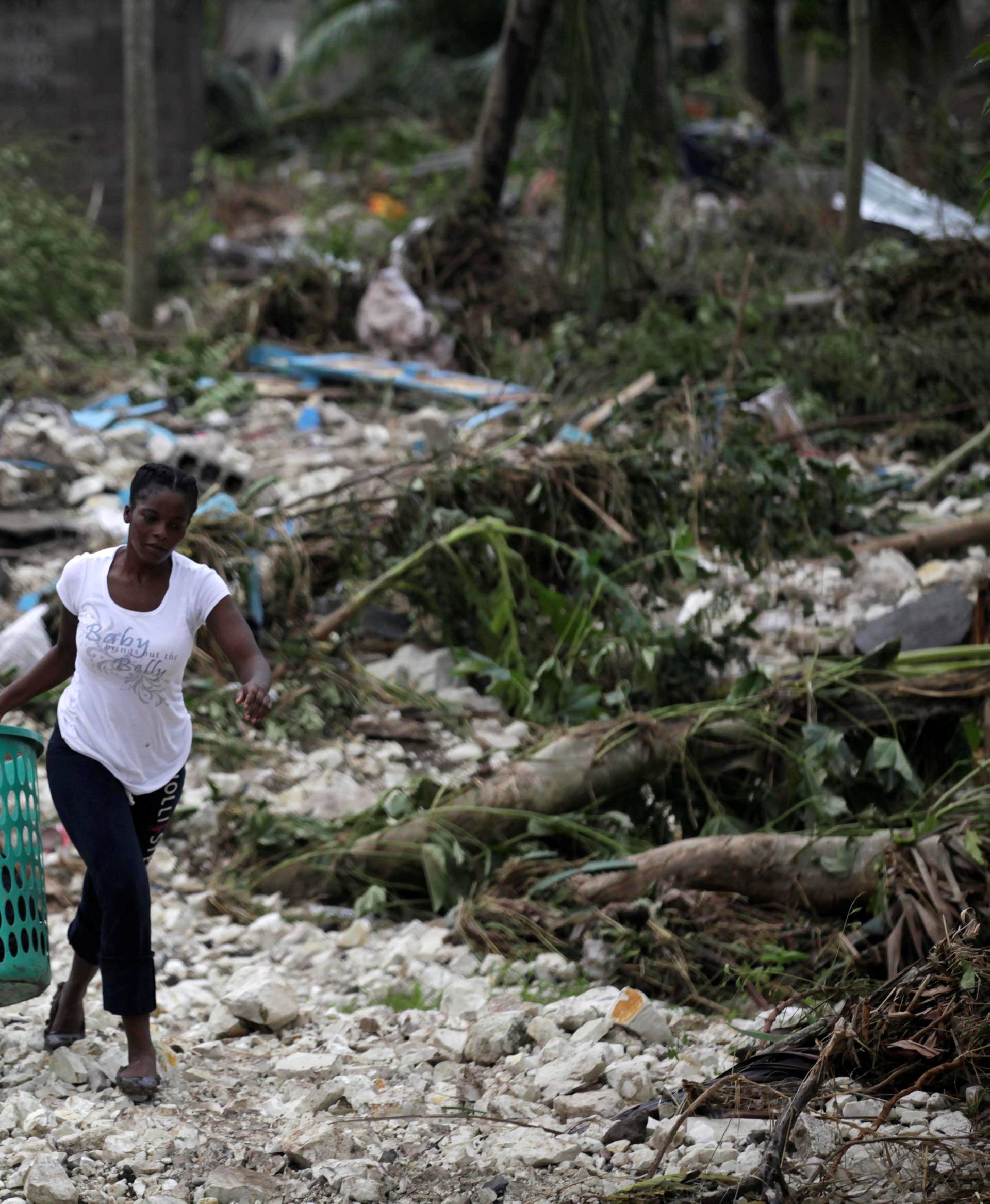 A woman carries a laundry basket in an area devastated by Hurricane Matthew in Cavaillon, Haiti