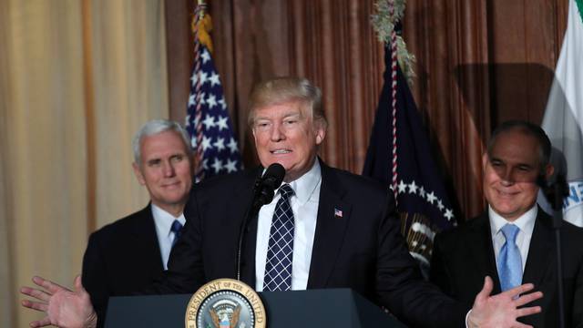 U.S. President Donald Trump speaks between Vice President Mike Pence and EPA Administrator Scott Pruitt prior to signing an executive order on "energy independence," eliminating Obama-era climate change regulations, during an event