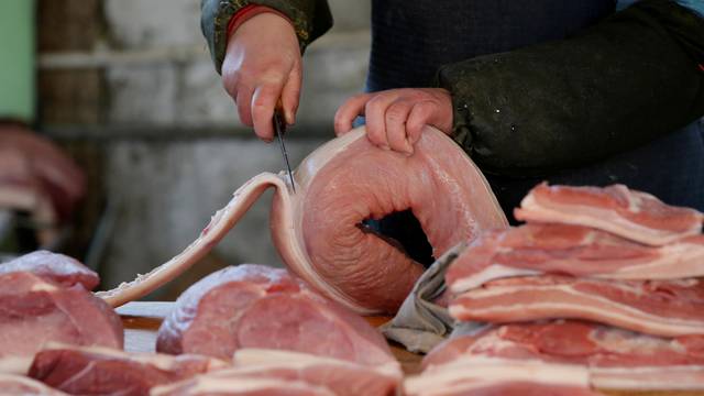 FILE PHOTO: A butcher cuts a piece of pork at a market in Beijing