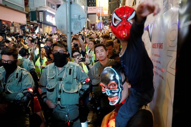 A man and his son wearing costumes stand in front of a riot police during Halloween in Lan Kwai Fong, Central district, Hong Kong