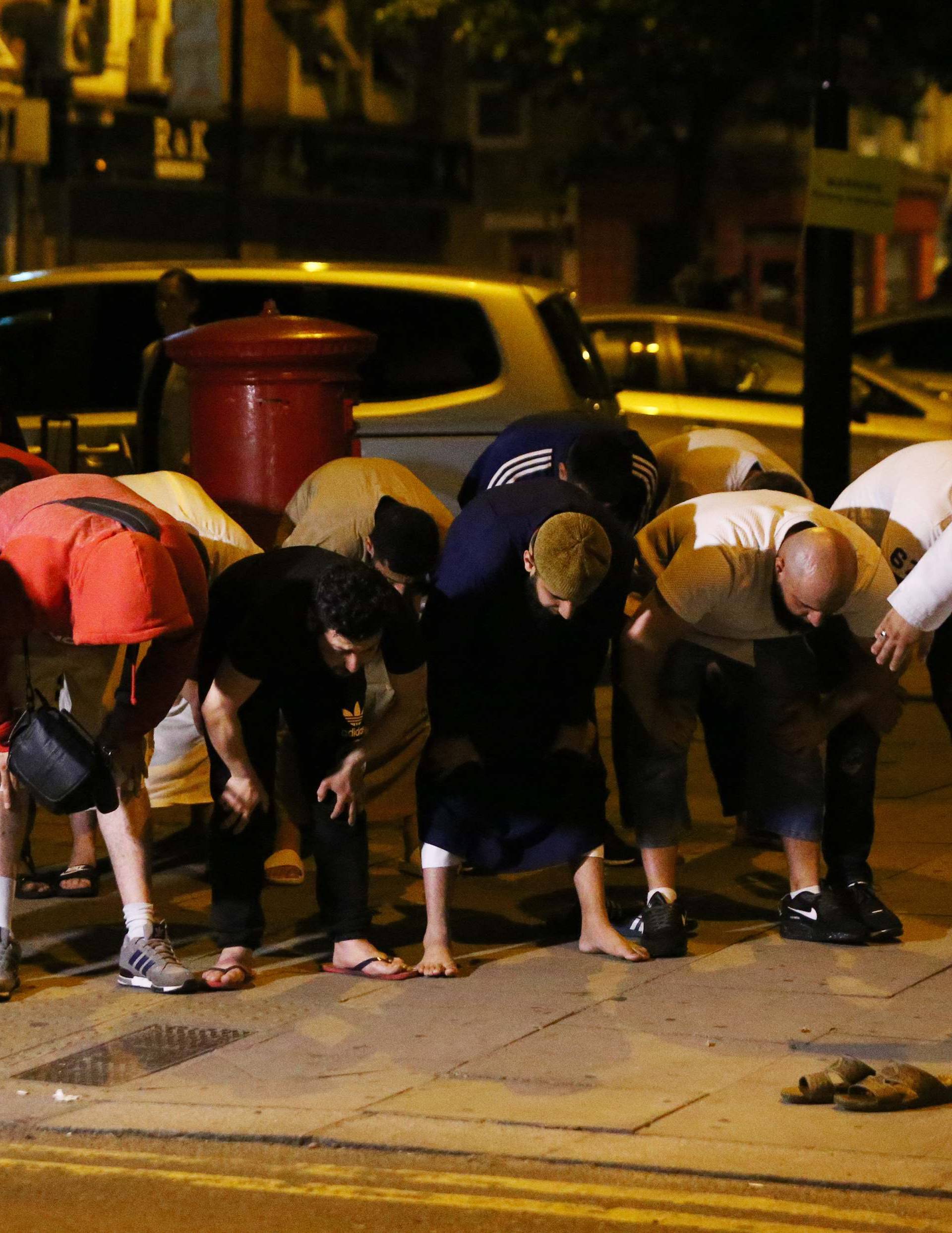 Men pray after a vehicle collided with pedestrians near a mosque in the Finsbury Park neighborhood of North London