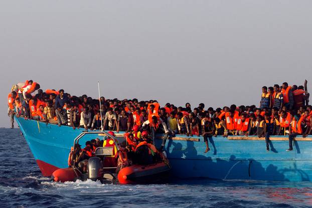 A rescue boat of the Spanish NGO Proactiva approaches an overcrowded wooden vessel with migrants from Eritrea, off the Libyan coast in Mediterranean Sea