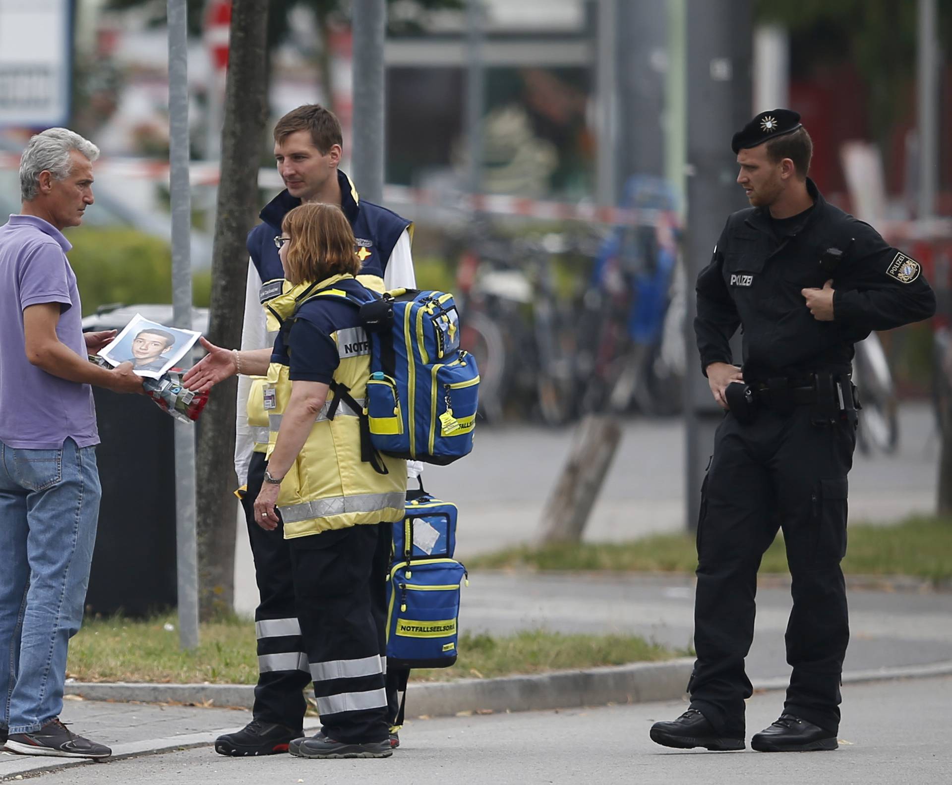Man holding photo he claims is his slain son speaks to emergency care team near Olympia shopping mall in Munich