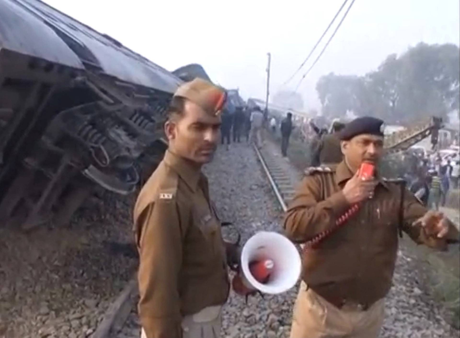 A police officer instructs people and rescuers at the site where a train derailed in Kanpur, in India's northern state of Uttar Pradesh