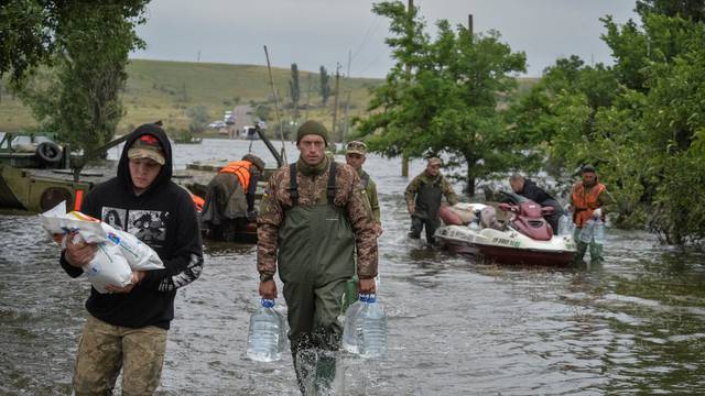 Ukrainian servicemen unload humanitarian aid for local residents after the Nova Kakhovka dam breached, in the flooded village of Afanasiivka