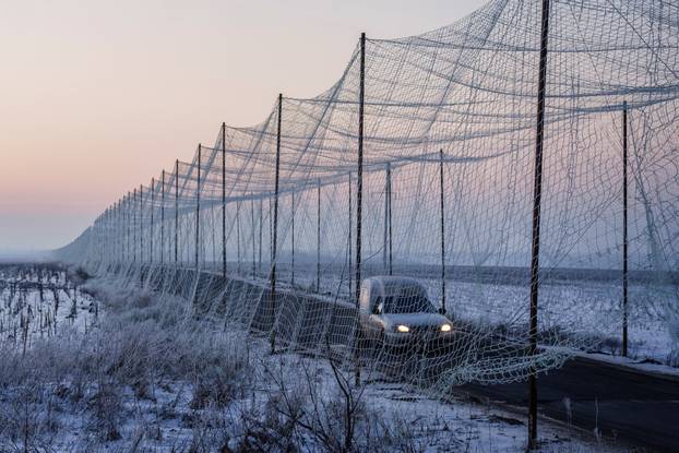 Car moves along a road covered with an anti-drone net in Kharkiv region