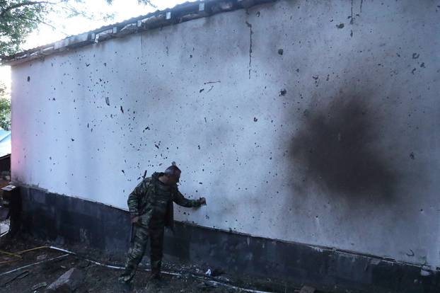 A man stands next to a building damaged by shelling in Jermuk