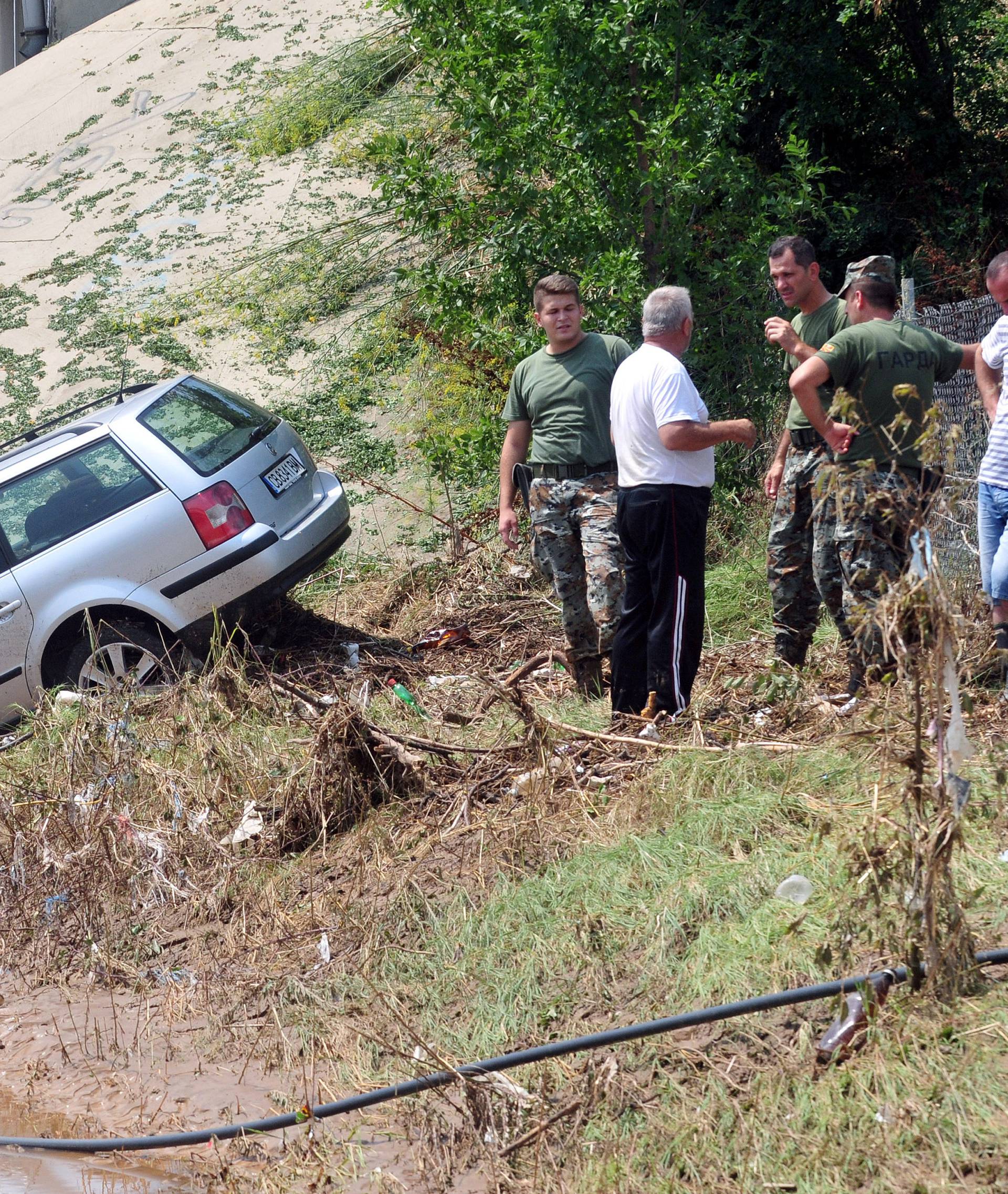 People look at a wrecked car after heavy floods in Cento near Skopje