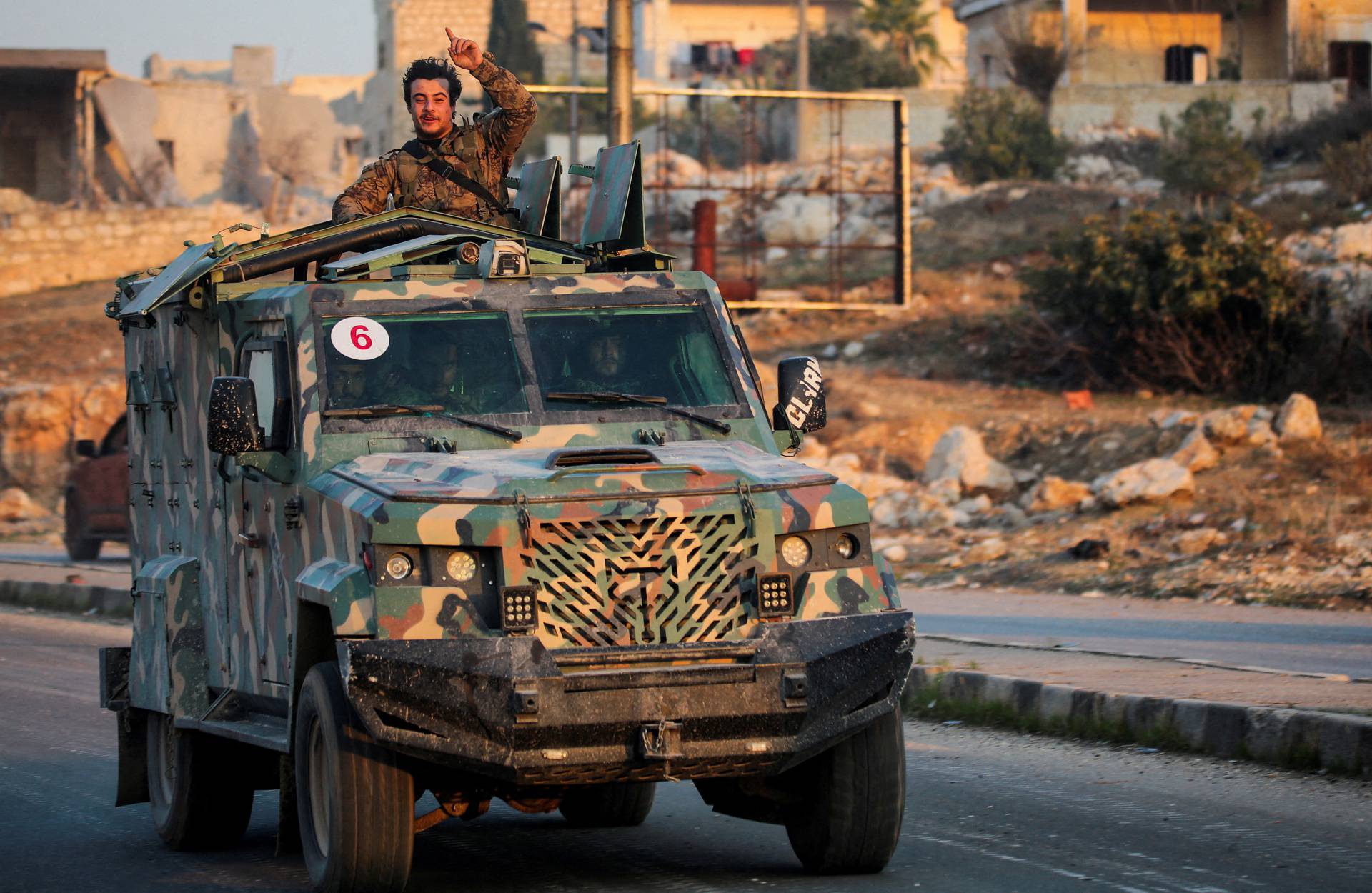 A rebel led by the Islamist militant group Hayat Tahrir al-Sham stands in the back of a vehicle in al-Rashideen