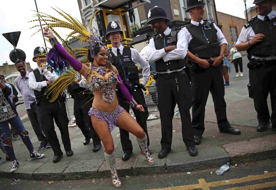 Police look as a performer dances during the Notting Hill Carnival in London