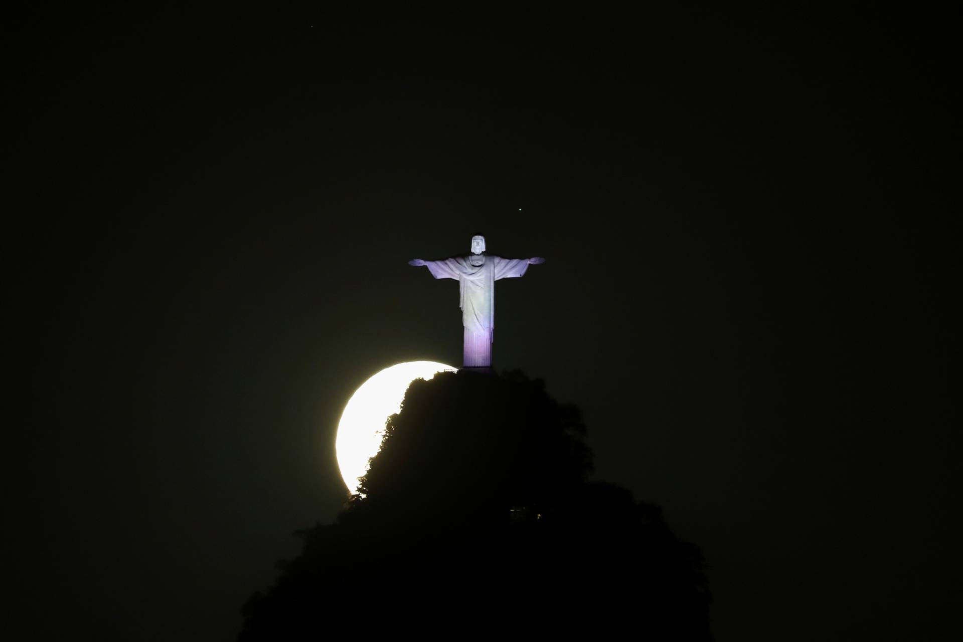 The super moon shines behind the Christ the Redeemer statue in Rio de Janeiro