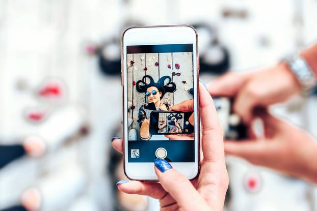 Friends taking photo of selfie pretty girl through two phones