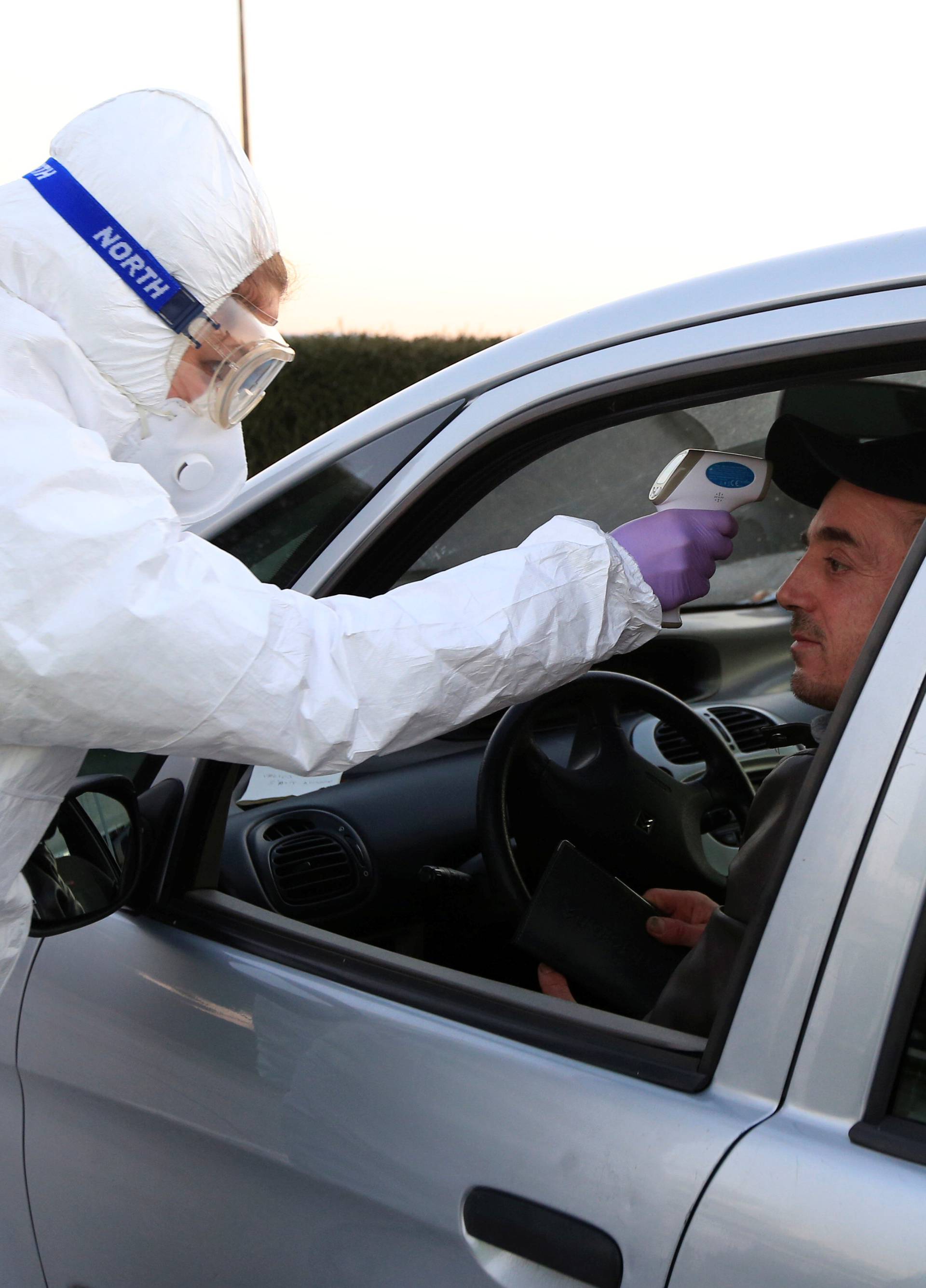 Medical staff checks a passenger in a car for coronavirus (COVID-19) at the border crossing with Italy in Vrtojba