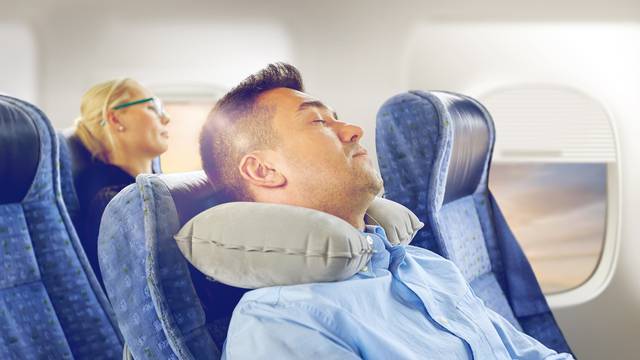 man sleeping in plane with cervical neck pillow