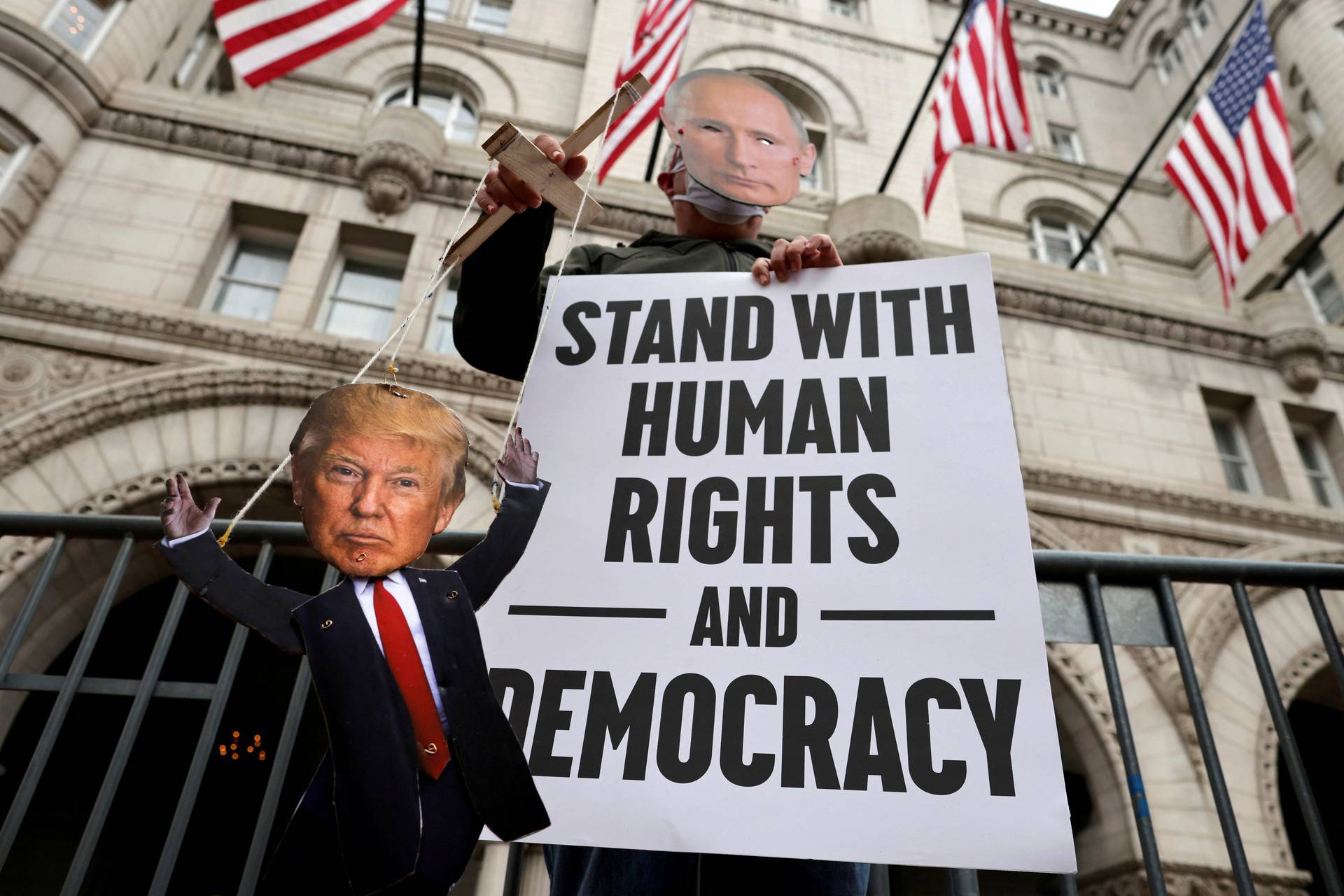 FILE PHOTO: A protester wears a face masks of Russia's President Vladimir Putin as he holds a marionette of U.S. President Donald Trump during a demonstration in front of the Trump International Hotel in Washington