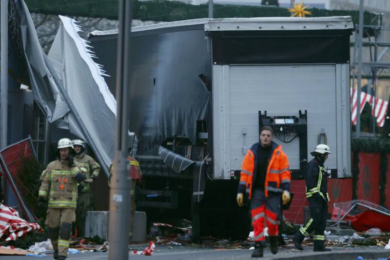Fire fighters walk in front of the truck which ploughed into a crowded Christmas market in the German capital last night in Berlin