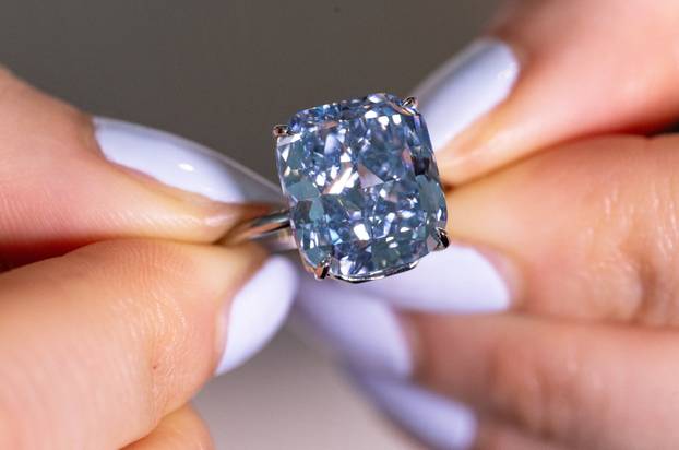 A Sotheby’s staff holds "The Mediterranean Blue" diamond during an auction preview in Geneva