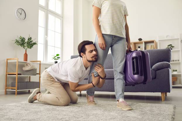 Young married couple breaking up and angry wife leaving home with packed suitcase