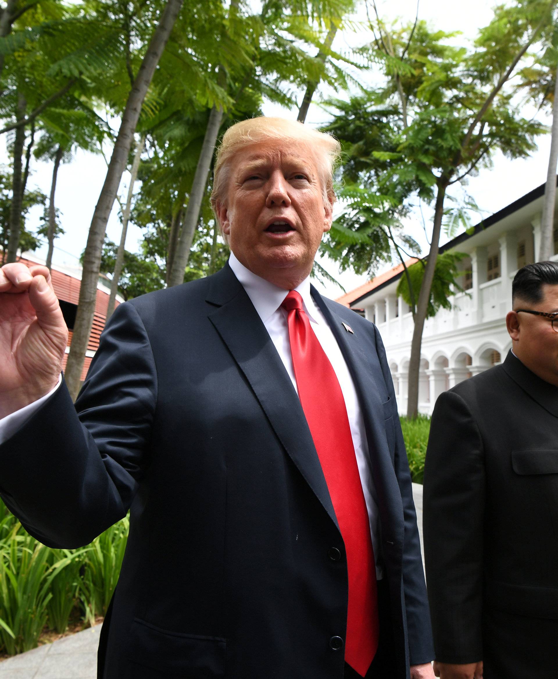 U.S. President Donald Trump gestures as he walks with North Korean leader Kim Jong Un in the Capella Hotel after their working lunch, on Sentosa island in Singapore