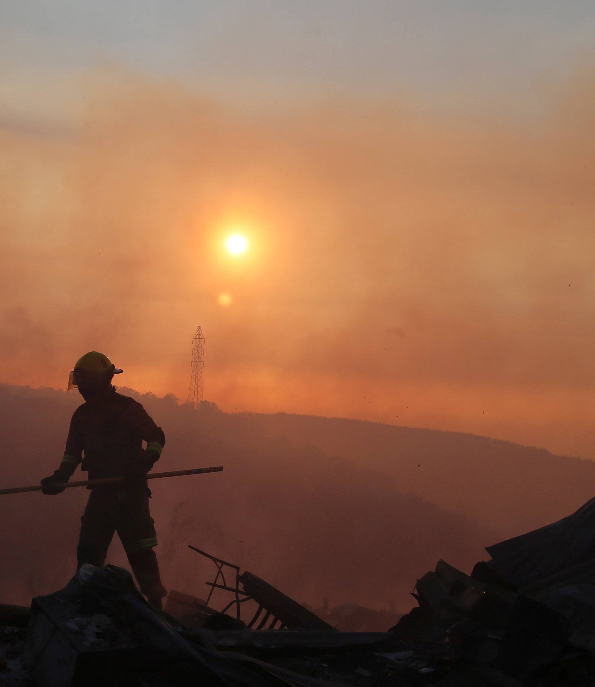 A firefighter removes the remains of a burned house on a hill, where more than 100 homes were burned due to forest fire but there have been no reports of death, local authorities said in Valparaiso, Chile