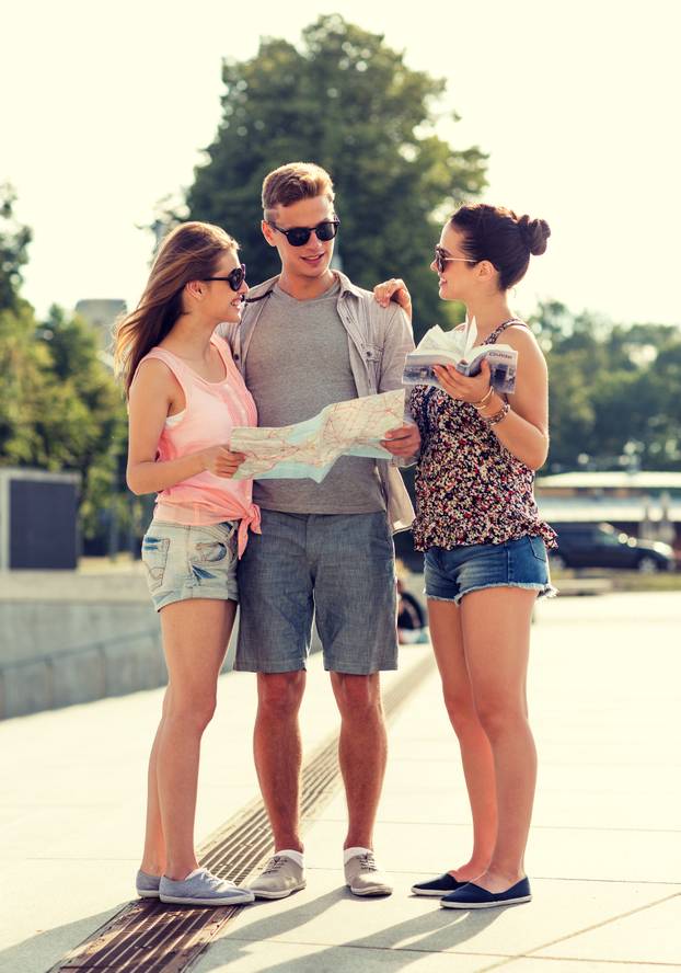 smiling friends with map and city guide outdoors