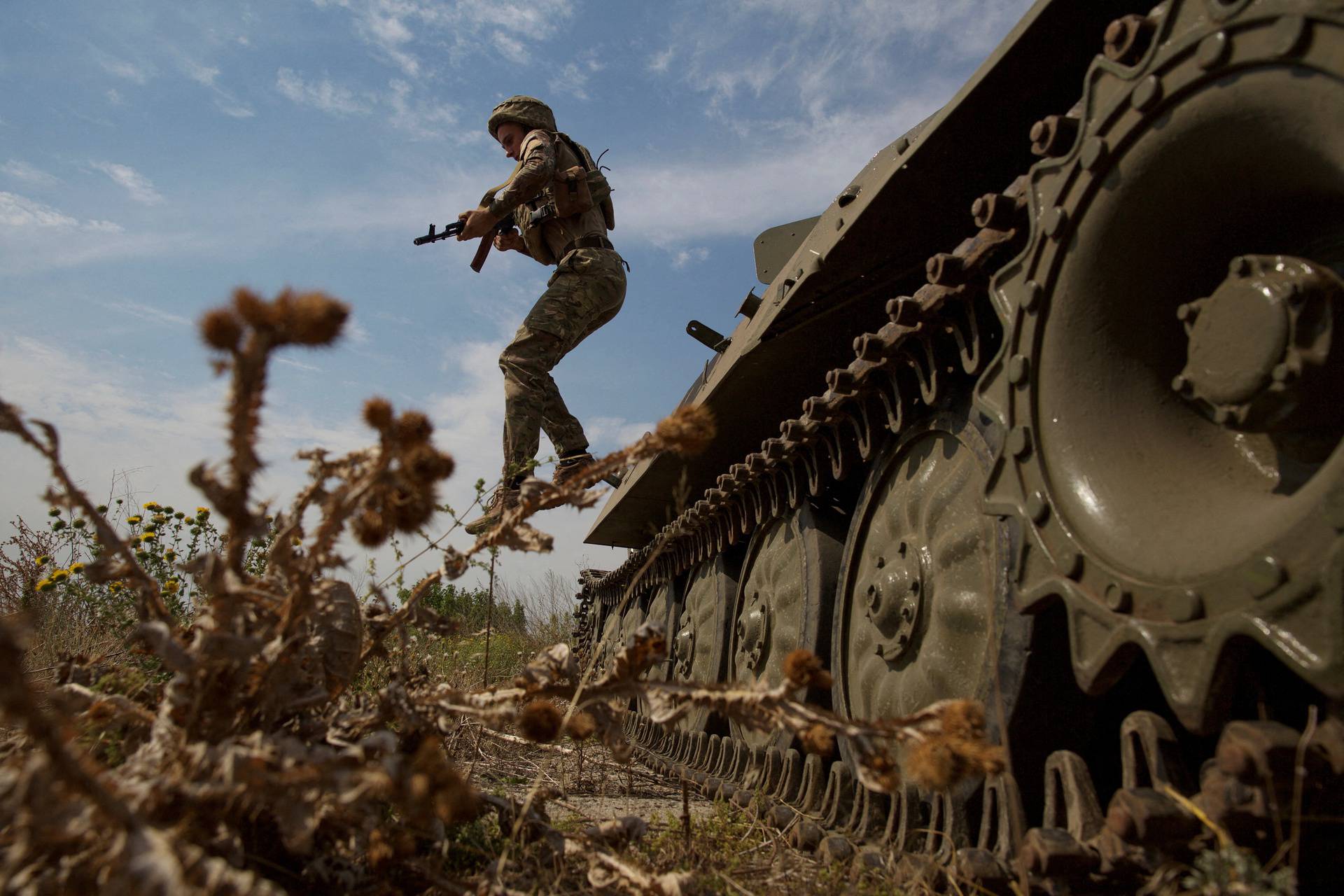 Ukrainian serviceman jumps from a military vehicle near a frontline in Mykolaiv region