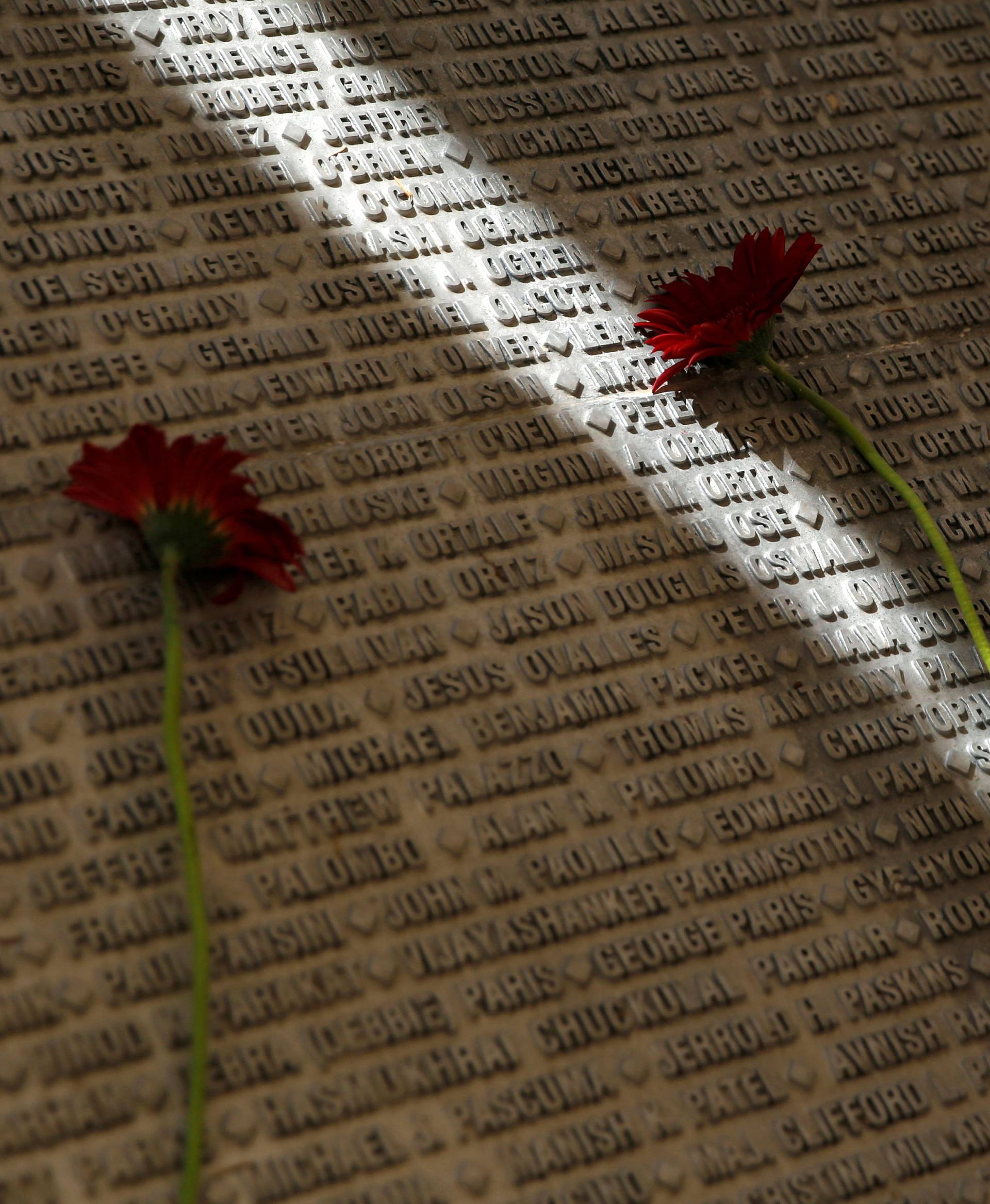 A man lays a flower on a monument engraved with names of victims of the September 11th attacks, during a memorial event marking the 15th anniversary of September 11, 2001 attacks in the U.S., at the 9/11 Living Memorial Plaza in Jerusalem