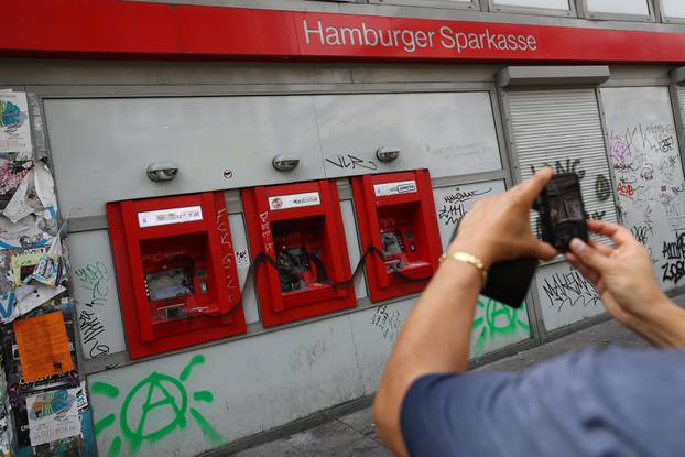 A woman takes a picture of damaged ATM during demonstrations at the G20 summit in Hamburg