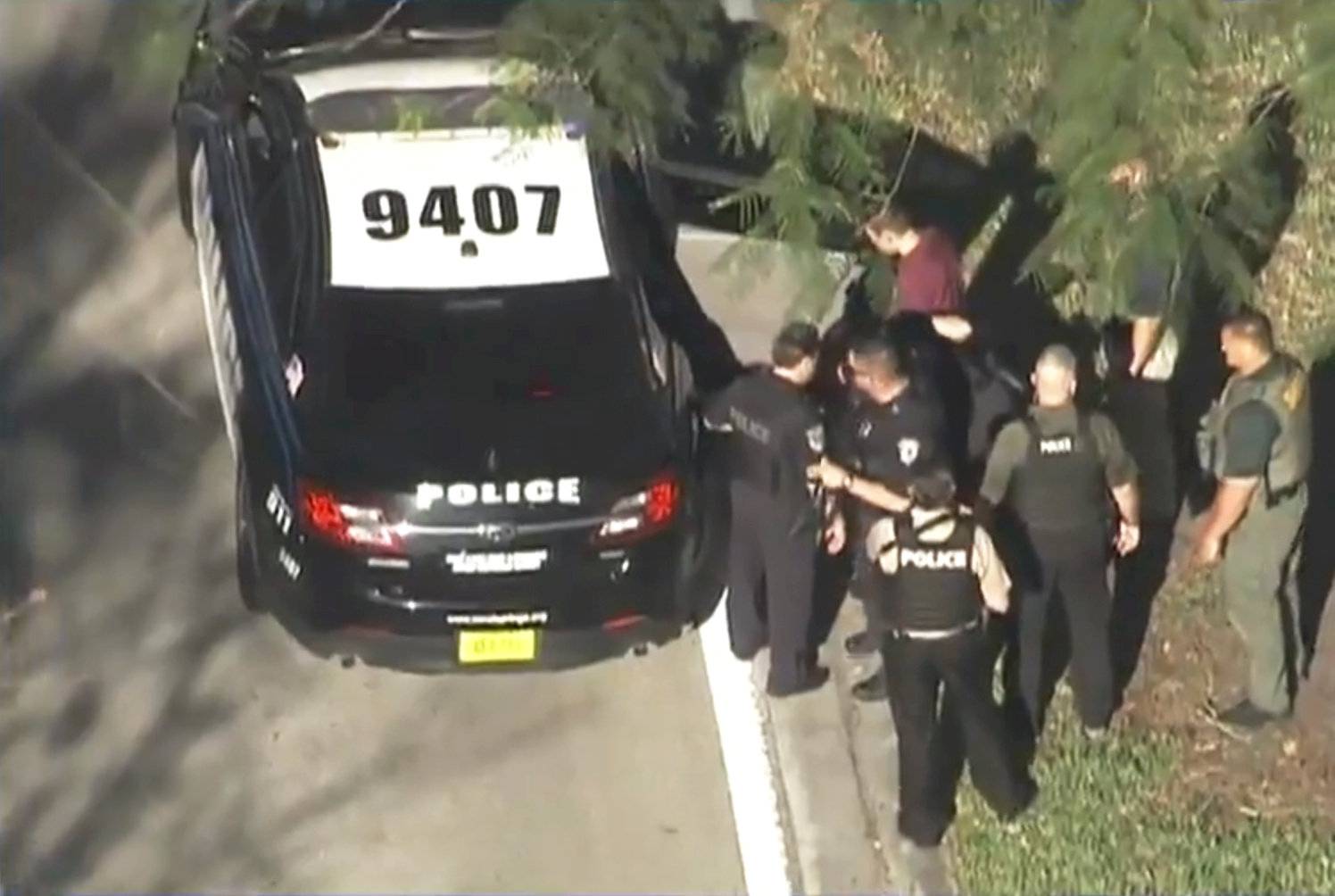 A man placed in handcuffs is led by police near Marjory Stoneman Douglas High School following a shooting incident in Parkland