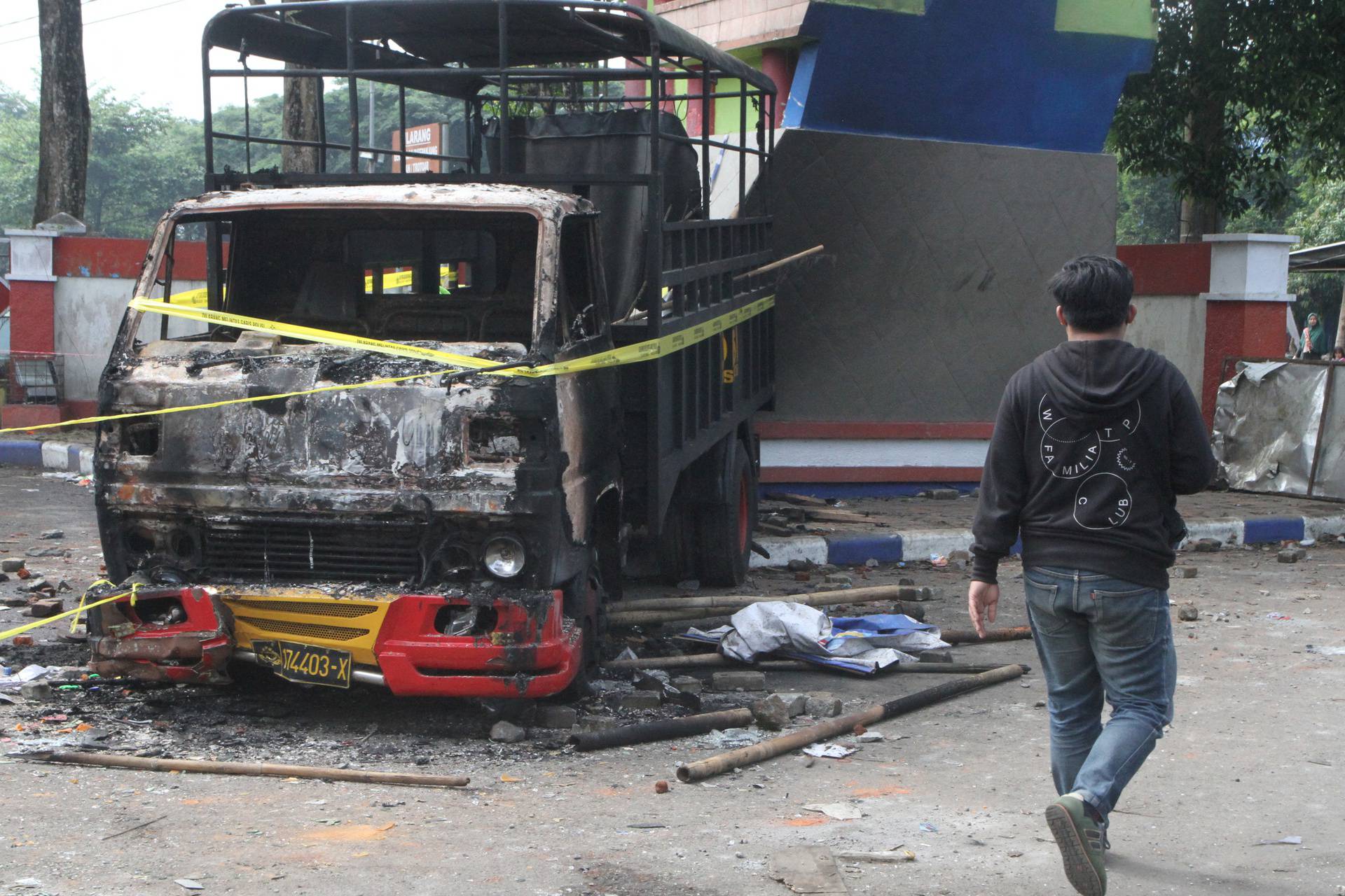 A man walks past a damaged truck is pictured following a riot after the league BRI Liga 1 football match between Arema vs Persebaya at Kanjuruhan Stadium