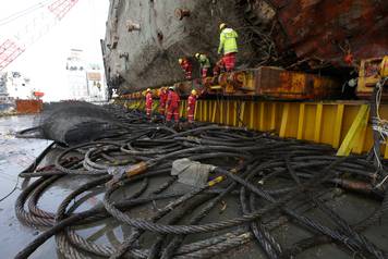 Workers work on the sunken ferry Sewol sitting on a semi-submersible ship during its salvage operations at the sea off Jindo