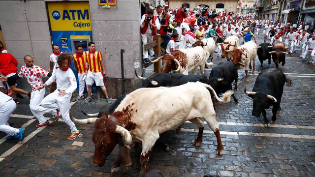 Participants run next to Vitoriano del Rio fighting bulls on Estafeta street on the fourth bullrun of the San Fermin festival in Pamplona, northern Spain on July 12, 2018