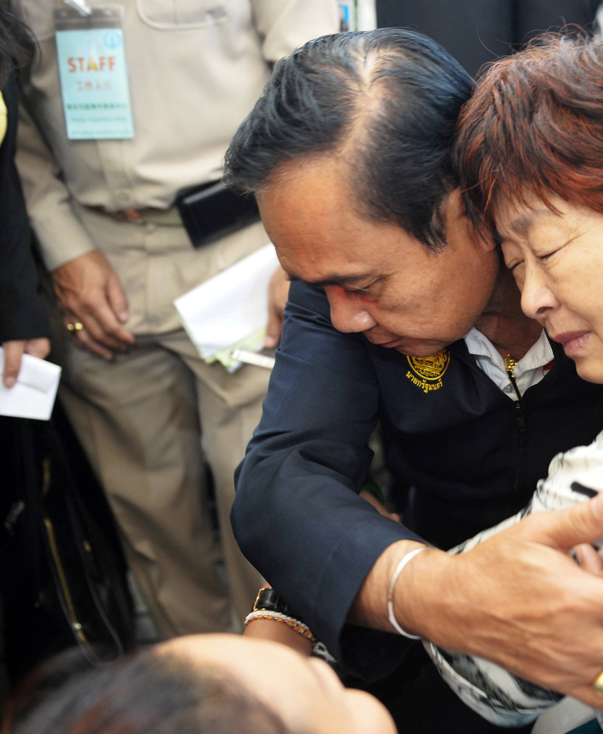 Thailand's Prime Minister Prayuth Chan-ocha comforts a relative of Chinese tourists involved in a sunken tourist boat accident at a hospital in Phuket