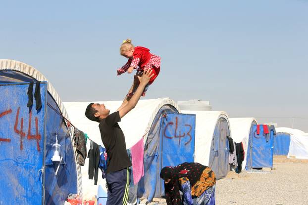 Displaced Iraqi man, who fled the Islamic State stronghold of Mosul, plays with his child in Khazer refugee camp, east of Mosul