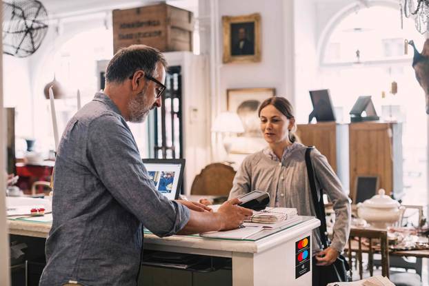 Owner using card reader in front of female customer at shop counter