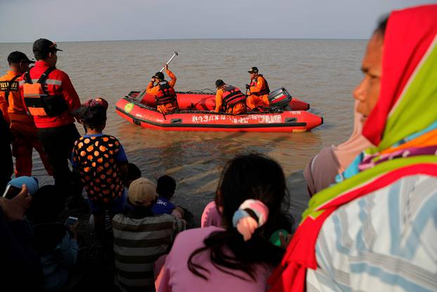 People watch rescue team members prepare the boat heading to the Lion Air, flight JT610, sea crash site off the coast of Karawang regency