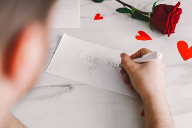 Happy Valentine's Day and romantic gesture. A man writes a valentine.