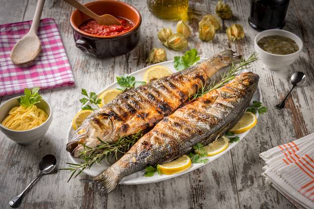 Grilled,Sea,Bass,Served,On,A,Plate,With,Various,Sauces