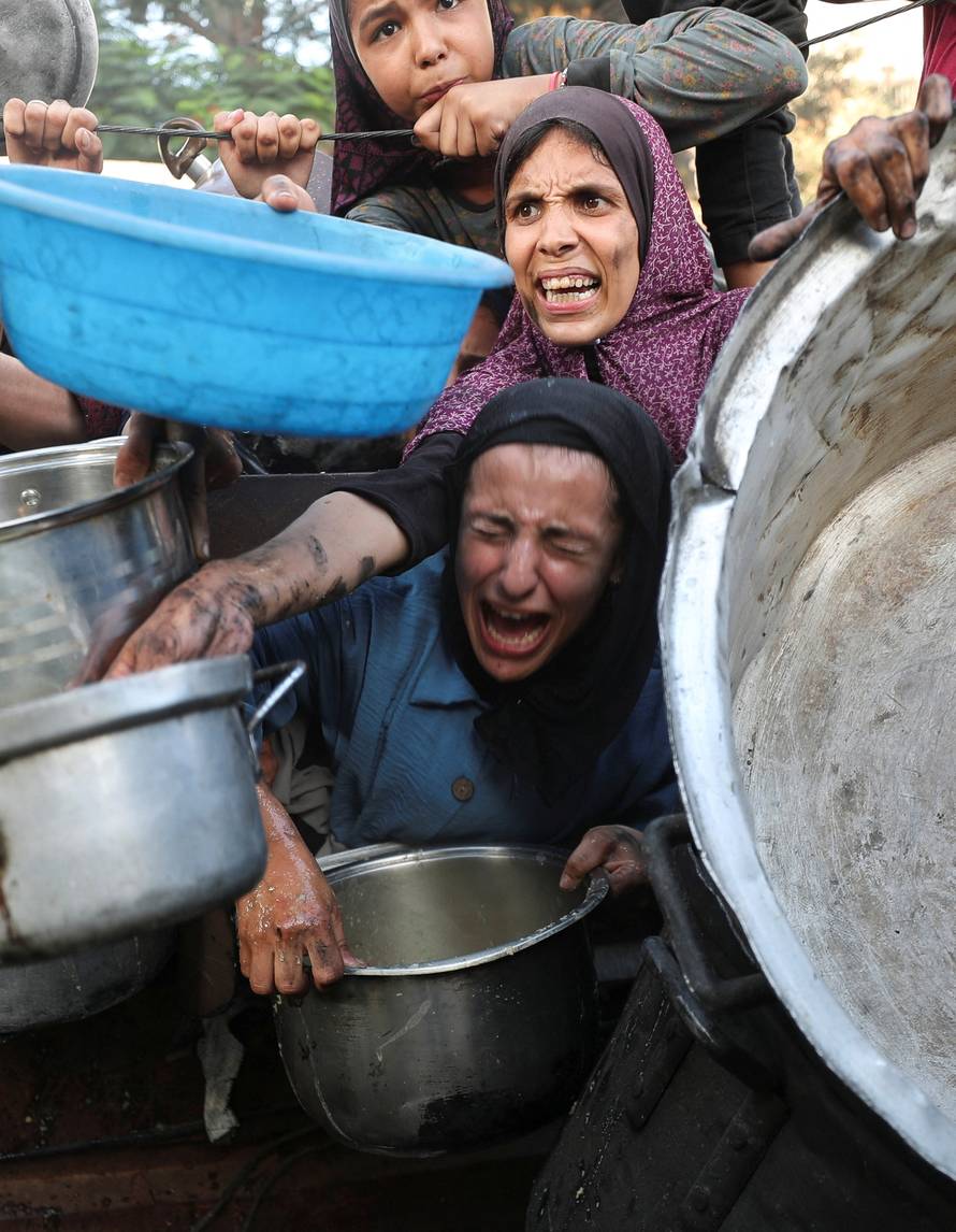 Palestinians wait to receive food from a charity kitchen, amid a hunger crisis, in Gaza City