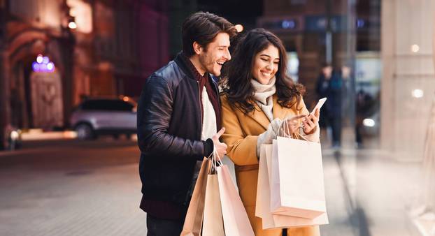 Young,Couple,With,Smartphone,Near,Shopping,Mall,,Standing,Near,Shop