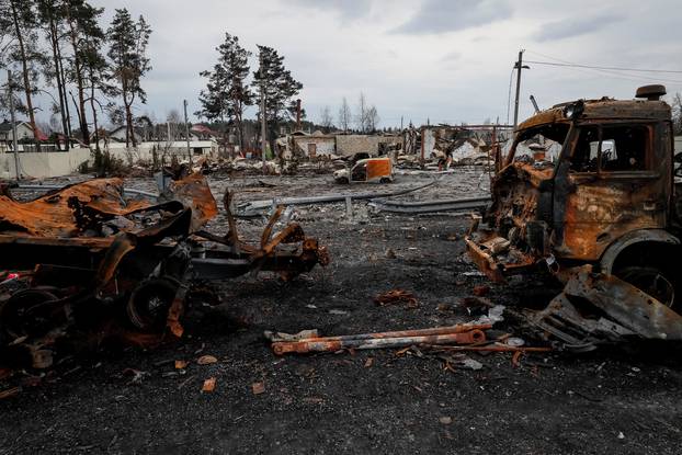 Burned column of military vehicles are seen near destroyed building on a highway in Kyiv region