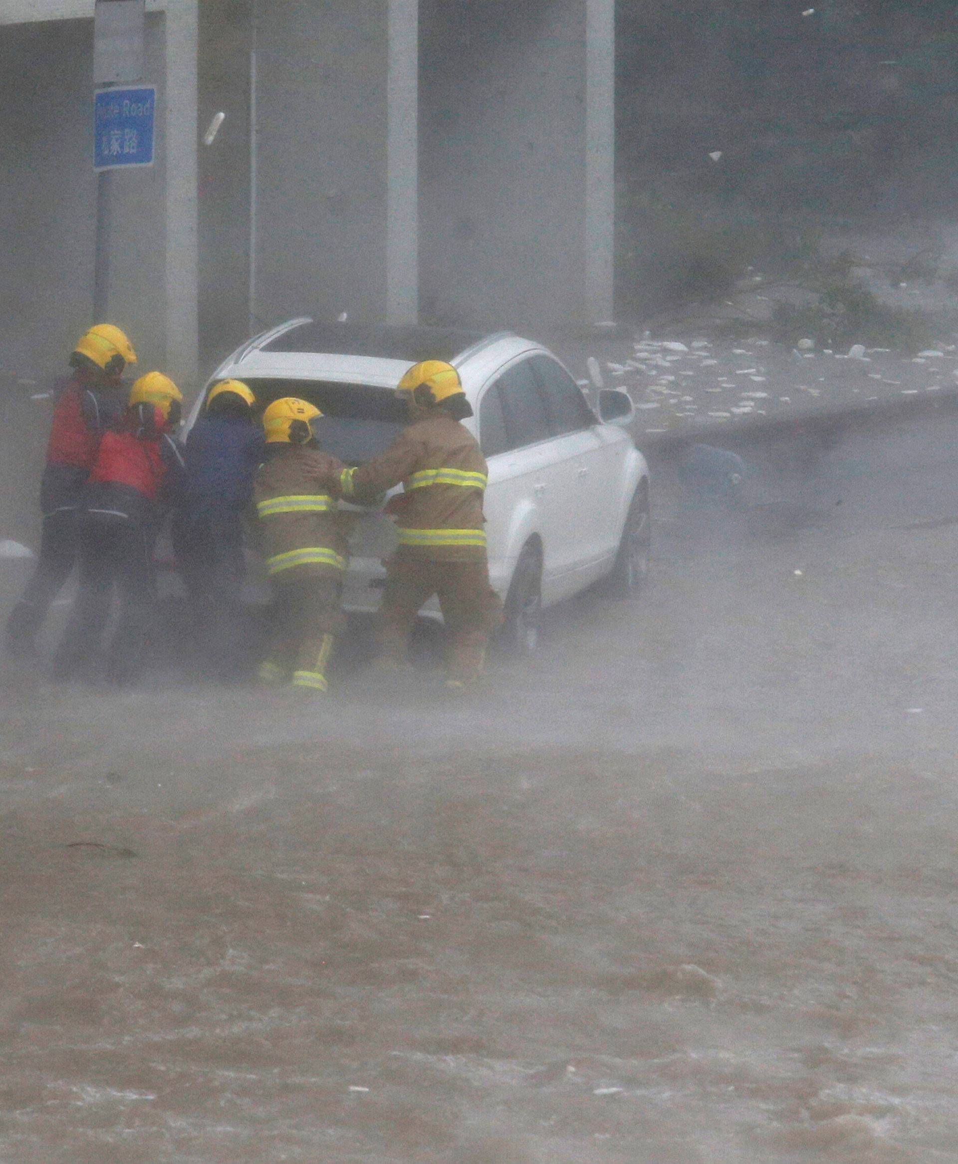 Firefighters push a car in flooded waters as high waves hit the shore at Heng Fa Chuen, a residental district near the waterfront, as Typhoon Mangkhut slams Hong Kong